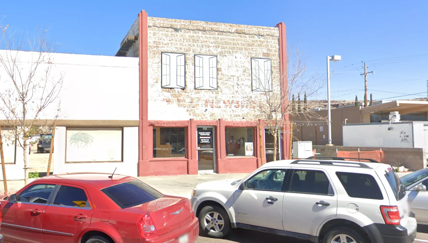 The Standard's building at 221 E. Beale Street in Kingman: a two-storey stone building with a red-painted facade and faded NEWSPAPER signage across the brick
